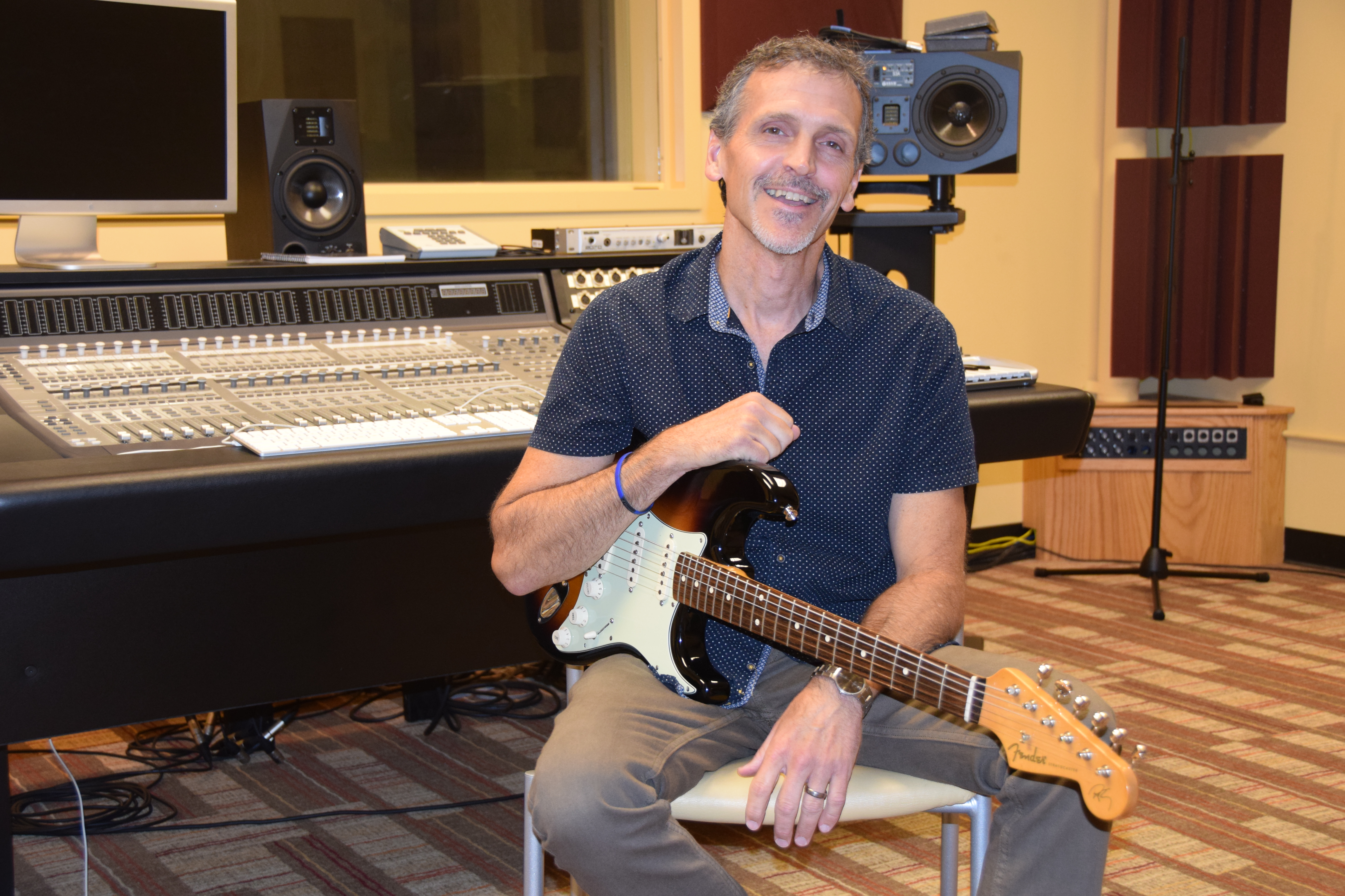 VU Associate Professor of Music Scott Mercer sits with a guitar on his lap in the John Mellencamp Audio Recording Studio at the Shircliff Humanities Center on the Vincennes Campus
